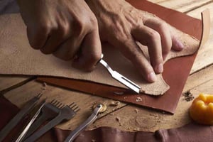 Man Shaving Leather on Wood Table